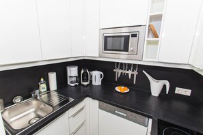 A modern kitchen with a stainless steel sink, a microwave, a coffee maker, and a knife block.
