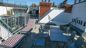 Una terrazza panoramica sul tetto con posti a sedere, tavoli e vista sulla città.