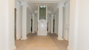A hallway with white columns, a central door with a sign, and a carpeted floor. - Vienna Hotspot - Staatsoper (Vienna)