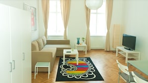 A modern living room with a sofa, a small table, a television, and a decorative rug. - Vienna Hotspot - Hundertwasser Künstlerviertel (Vienna)