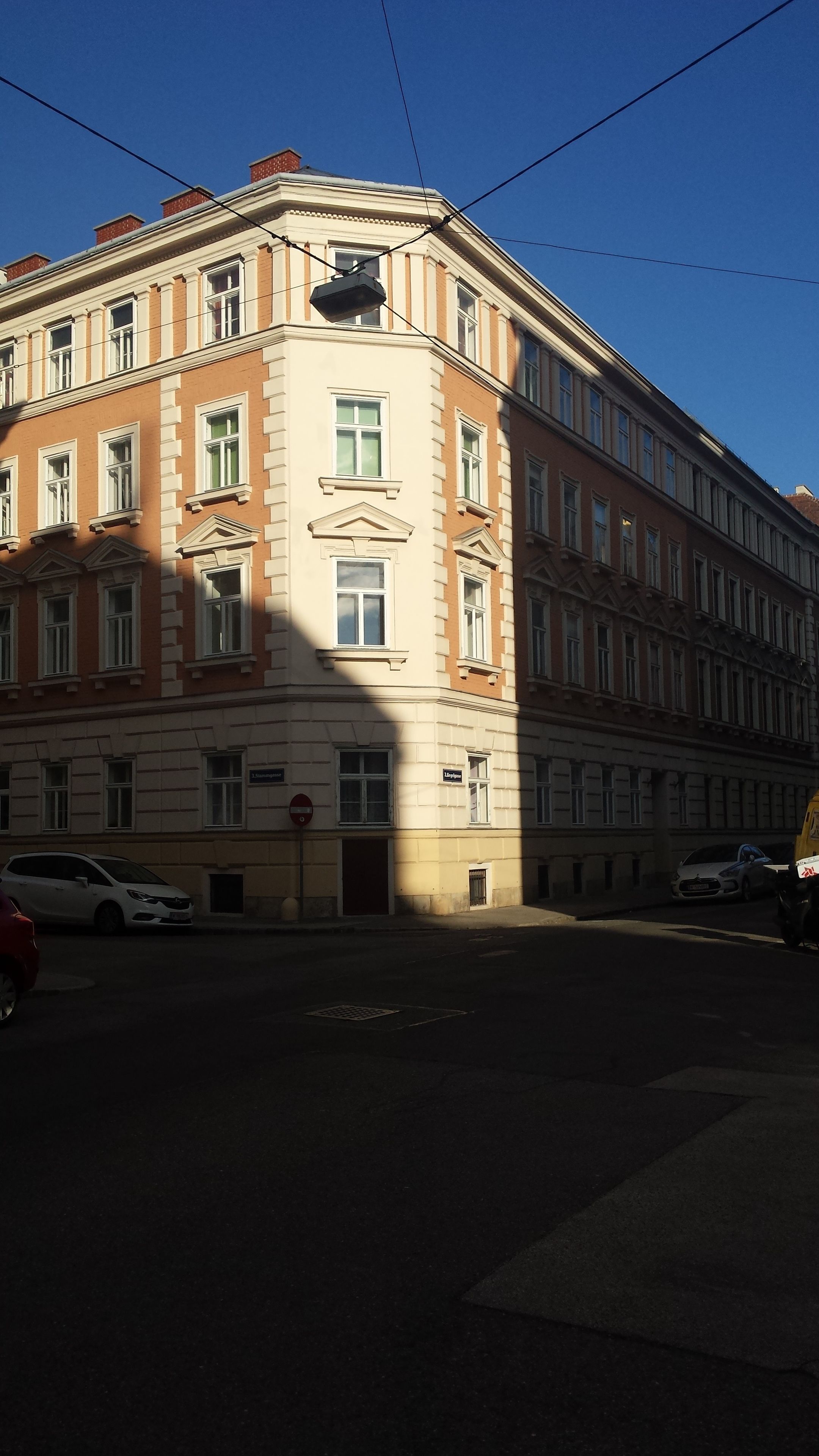 A corner building with classical architecture, multiple windows, and a street in front.