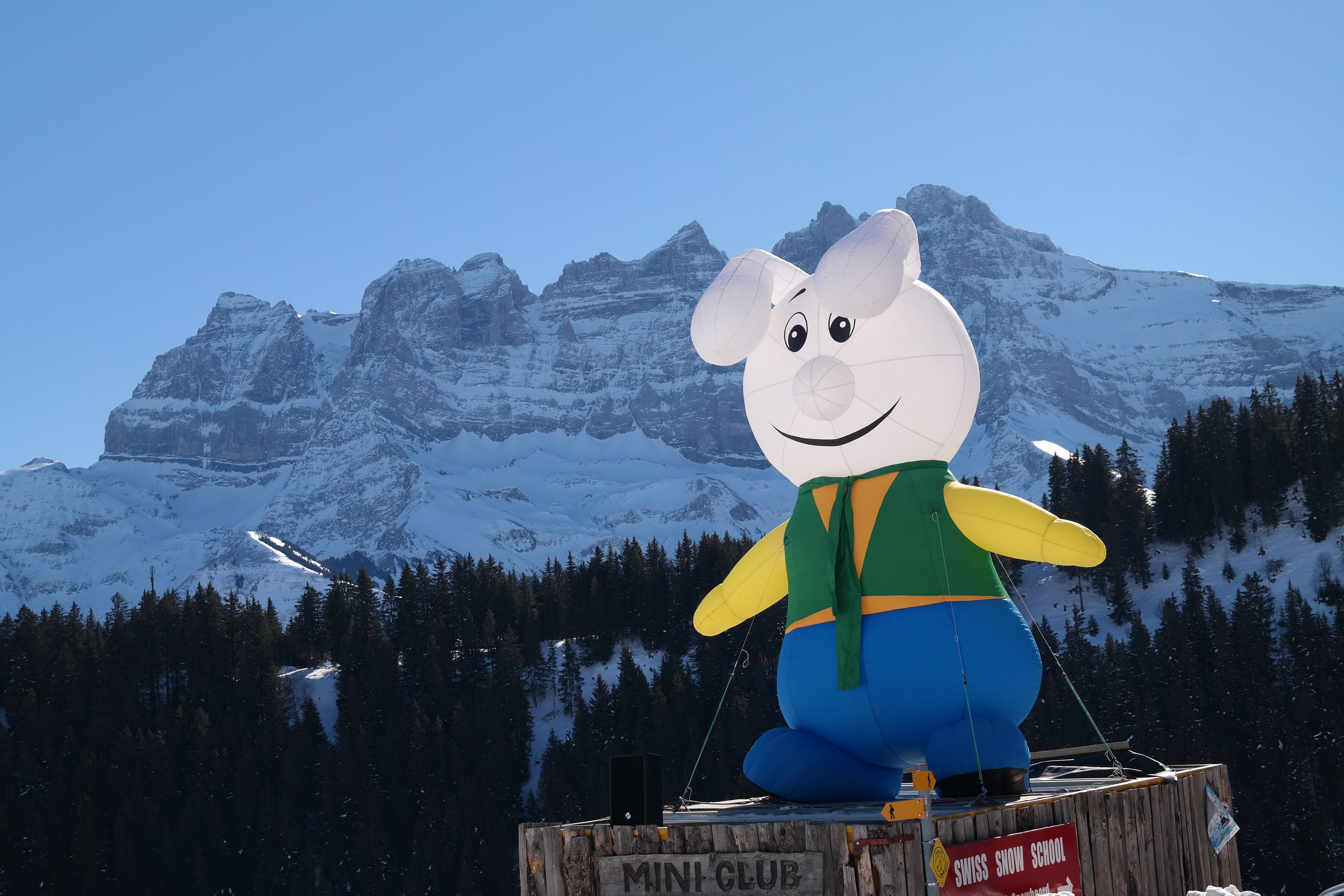 A large inflatable character in front of a snow-covered mountain.