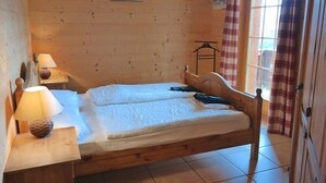A wooden-framed bed with a white mattress, a bedside lamp, and a small table.