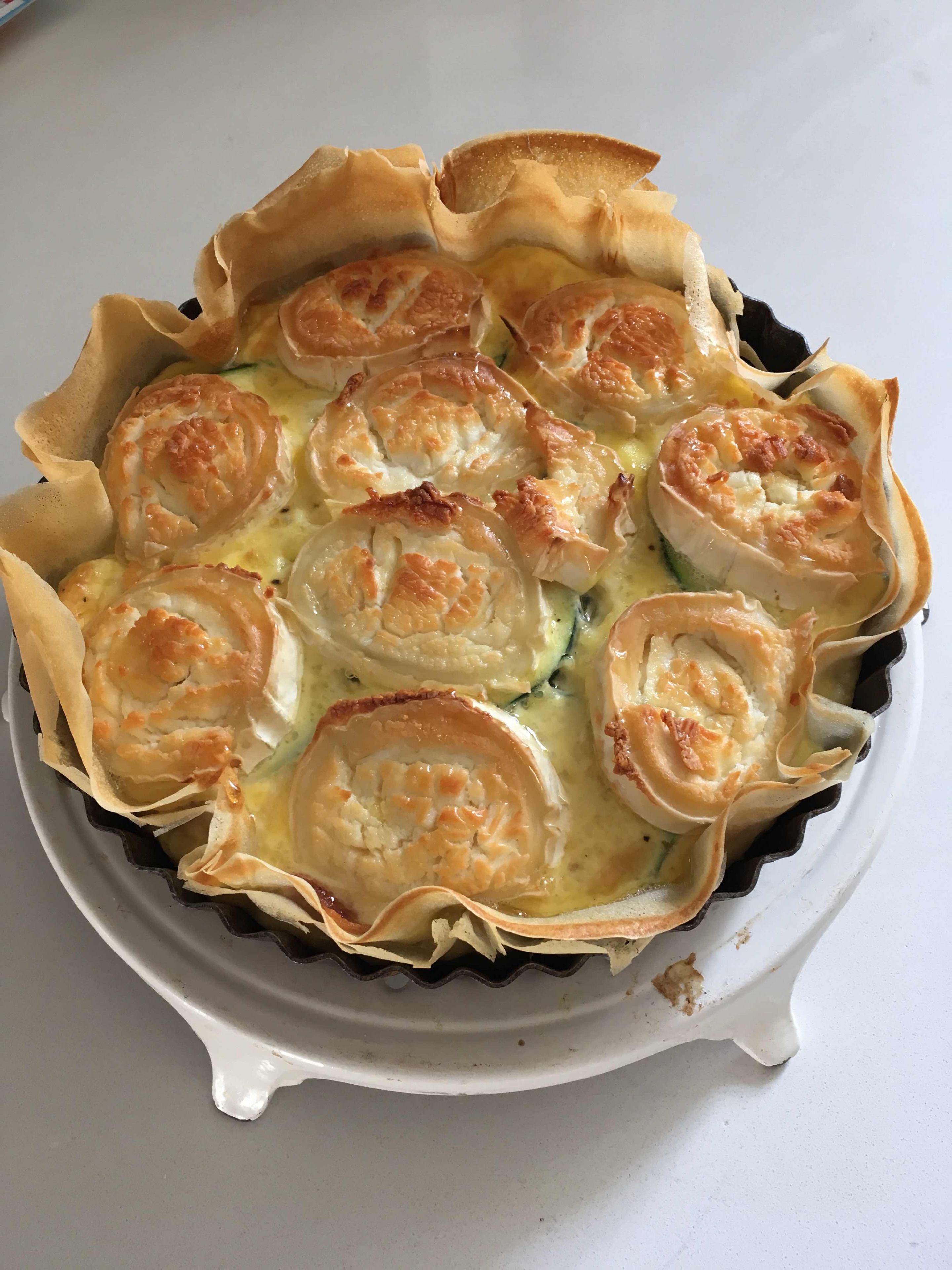 A quiche with puff pastry edges in a black baking dish.