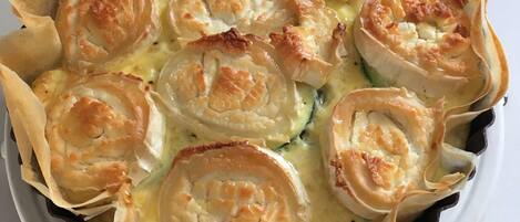 A quiche with puff pastry edges in a black baking dish.