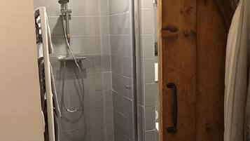 A bathroom with a shower, tiled walls, and a wooden door.