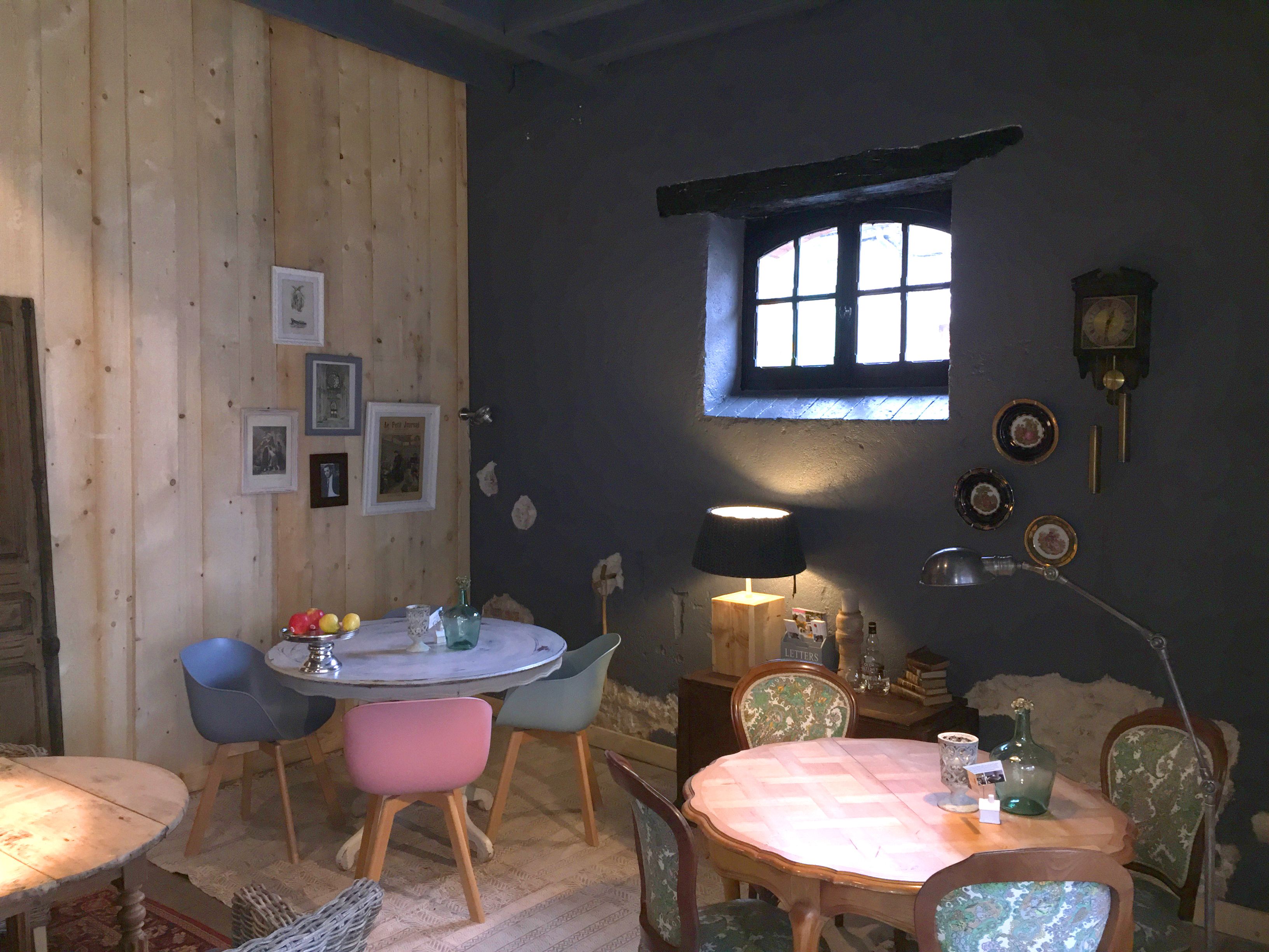 Un cuarto acogedor con paredes de madera, una mesa redonda y sillas. Hay una ventana con vistas, un reloj y cuadros en la pared.