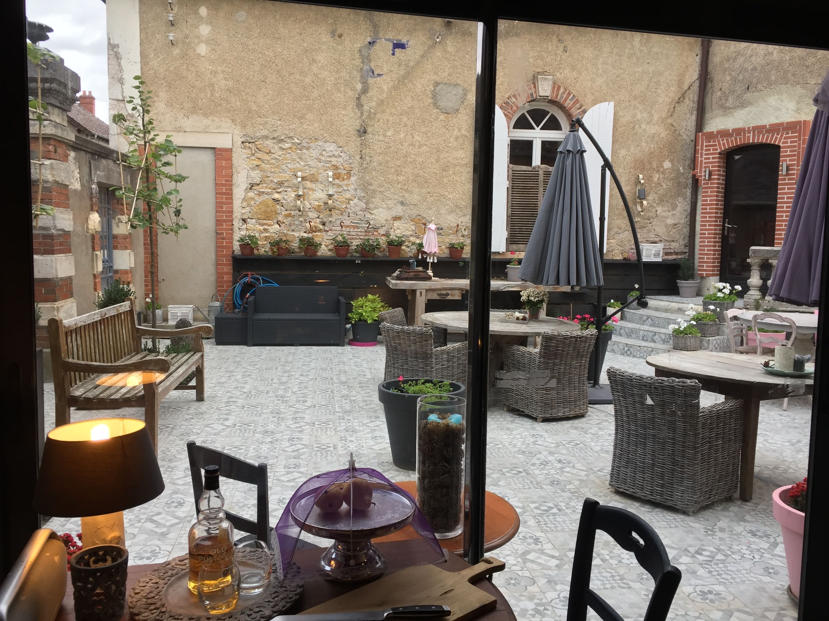 A cozy outdoor seating area with wicker furniture, a table with a lamp, and potted plants.
