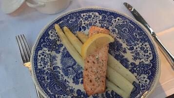 Un plato con salmón, limón y papas sobre un plato de diseño azul y blanco.
