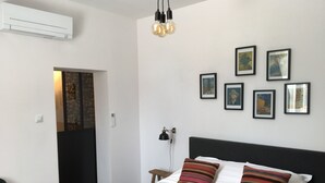 Une chambre à coucher avec un lit, un bureau et une chaise. Des tableaux encadrés ornent le mur.