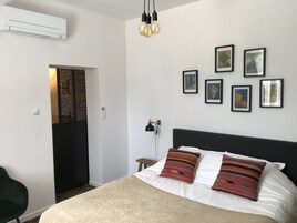 Un dormitorio con una cama, un escritorio y una silla. Hay cuadros en la pared.