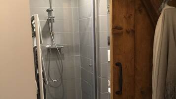 Een douche met een glazen deur, betegelde wanden en een vloer met een patroon.