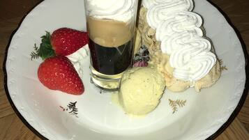 Un plat de postre amb una porció de pastís coberta de nata muntada, una bola de gelat i dues freses.