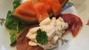 Een bord met parmaham, meloen en garnering.