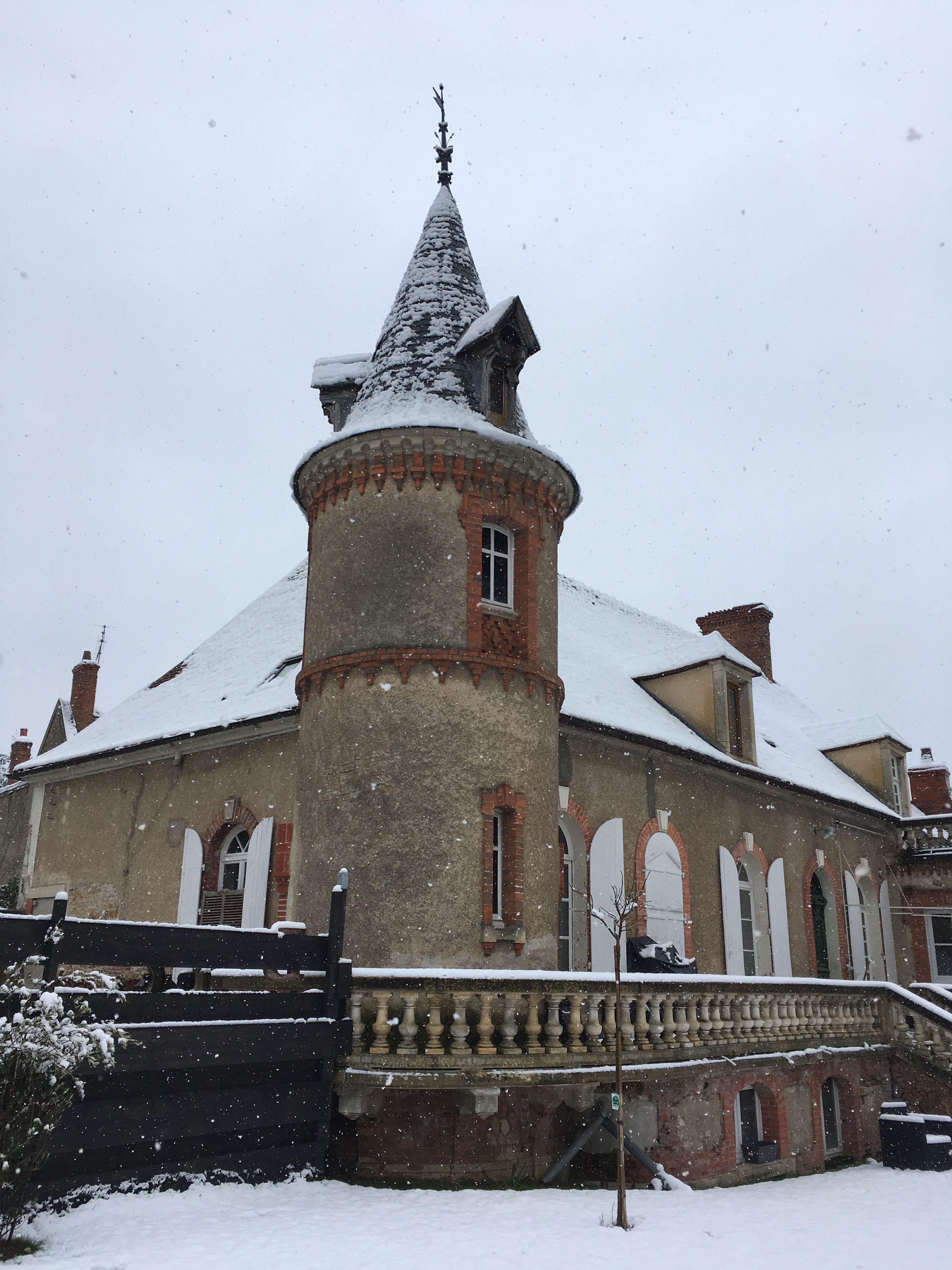 Un bâtiment historique doté d’une tourelle et de fenêtres en arc de cercle, entouré de neige.