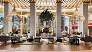 A spacious lobby with a central seating area, large windows, and hanging pendant lights. - Palm Beach Singer Island Beach Resort Condos (Singer Island)