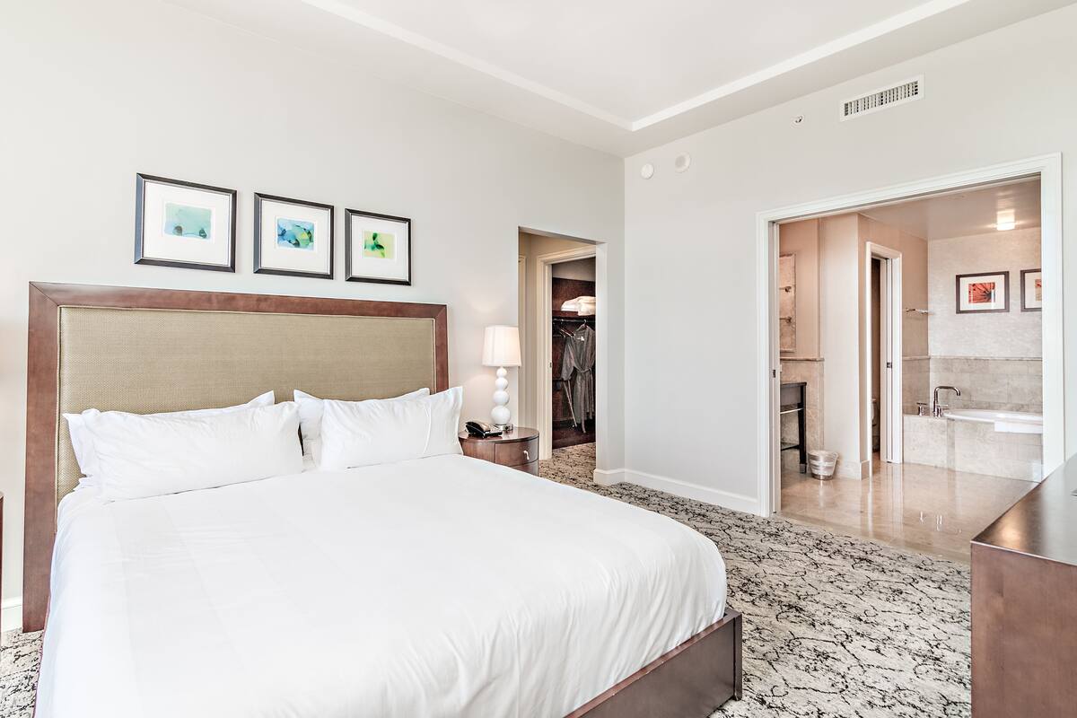 A hotel room with a large bed, a bedside table, a lamp, and a framed picture on the wall.