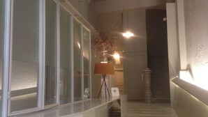 A hallway with a bench, a lamp, and a staircase. - Hostal Argo (Barcelona)
