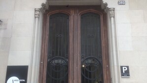 A building with a double door, a balcony with a metal railing, and a sign indicating a parking area. - Hostal Argo (Barcelona)