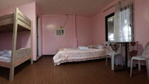 A room with a bunk bed, a single bed, a desk with a chair, and a window with curtains. - Old Parola Seaside Cottages (Baler)