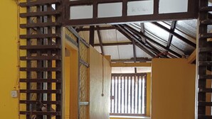 A room with a wooden bed, a small window, and a door with a metal gate. - Old Parola Seaside Cottages (Baler)