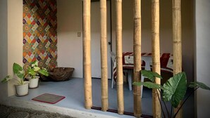 A room with a bamboo partition, a patterned wall, and a dining area with a table and chairs. - Old Parola Seaside Cottages (Baler)