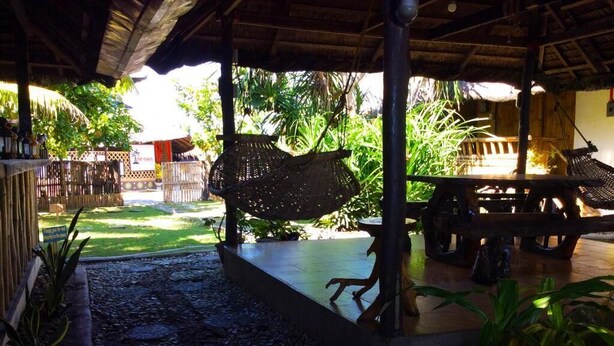 A covered outdoor area with a thatched roof, a wooden bench, and a hanging woven basket. - Old Parola Seaside Cottages (Baler)