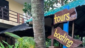 A wooden signpost with arrows pointing to activities like tours, boating, and surfing. - Old Parola Seaside Cottages (Baler)