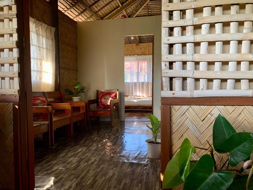 Una habitación con piso de madera, una cama con cabecera blanca, una silla de madera y una planta en maceta.