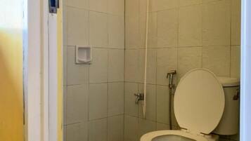 A small bathroom with a toilet, a shower, and a sink.