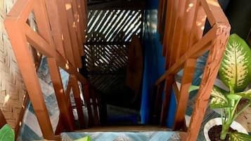A wooden staircase with a patterned floor leading to a dark interior space.