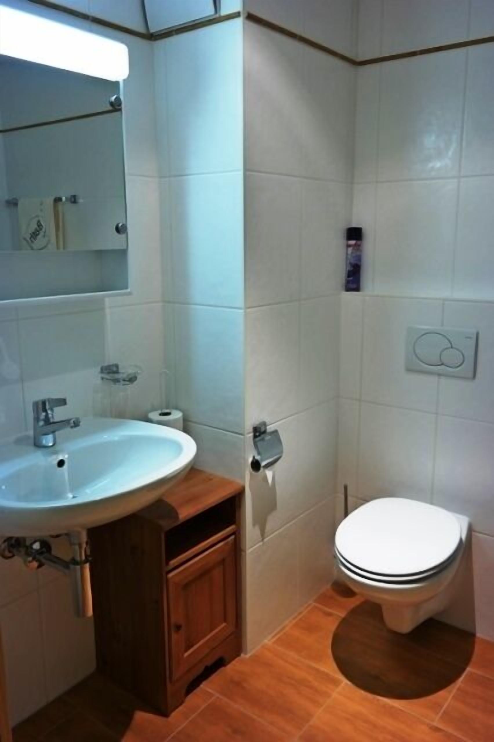 Un baño con lavamanos, espejo y retrete blancos.