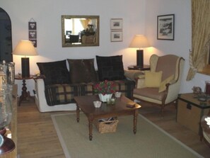 A living room with a sofa, armchairs, a coffee table, and two lamps.