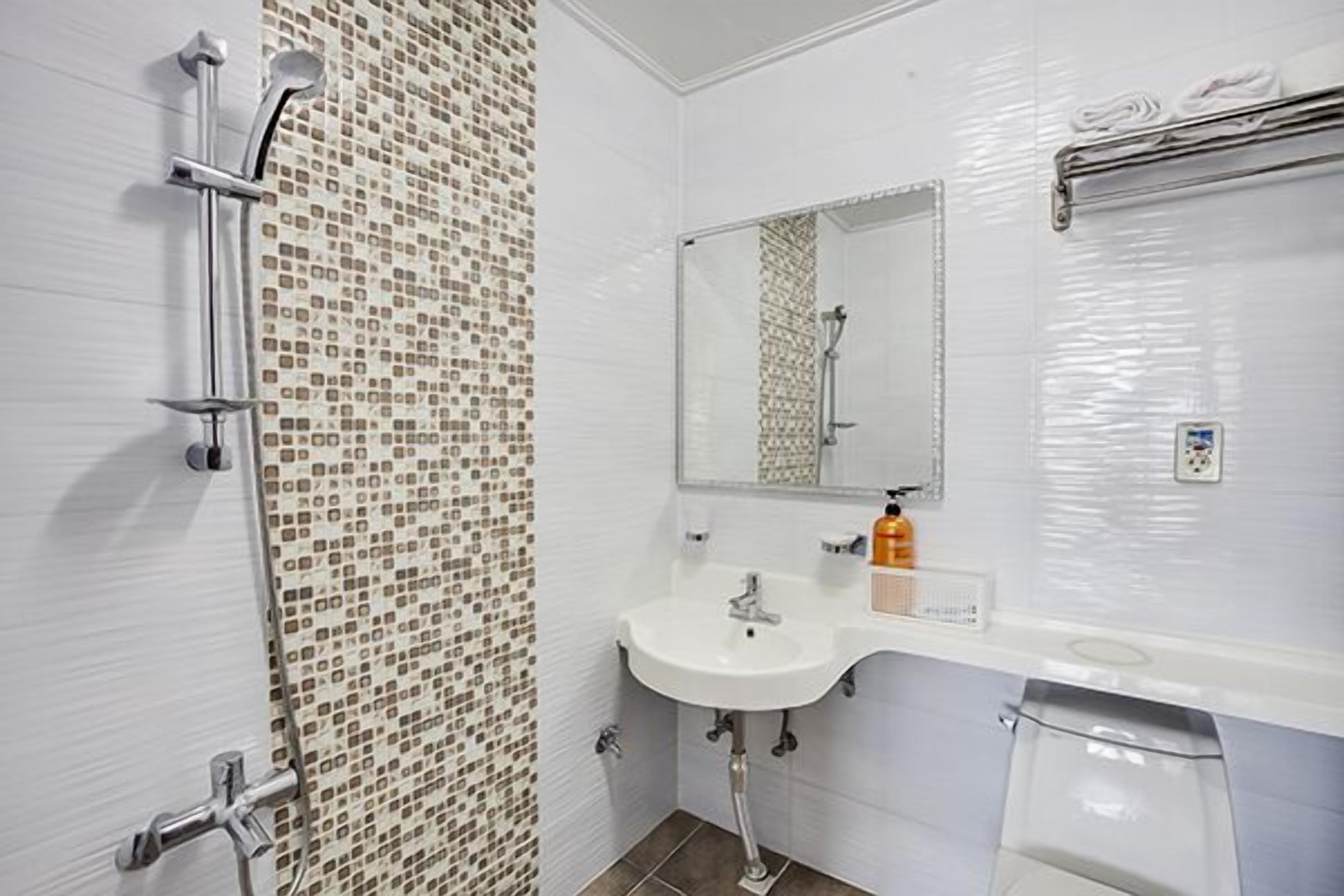 A bathroom with a shower, sink, and mirror.