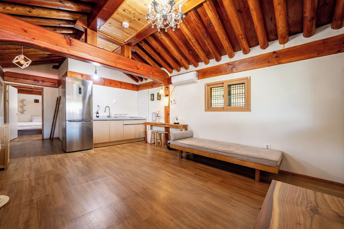 A compact kitchen with wooden beams, a built-in refrigerator, and a bench.