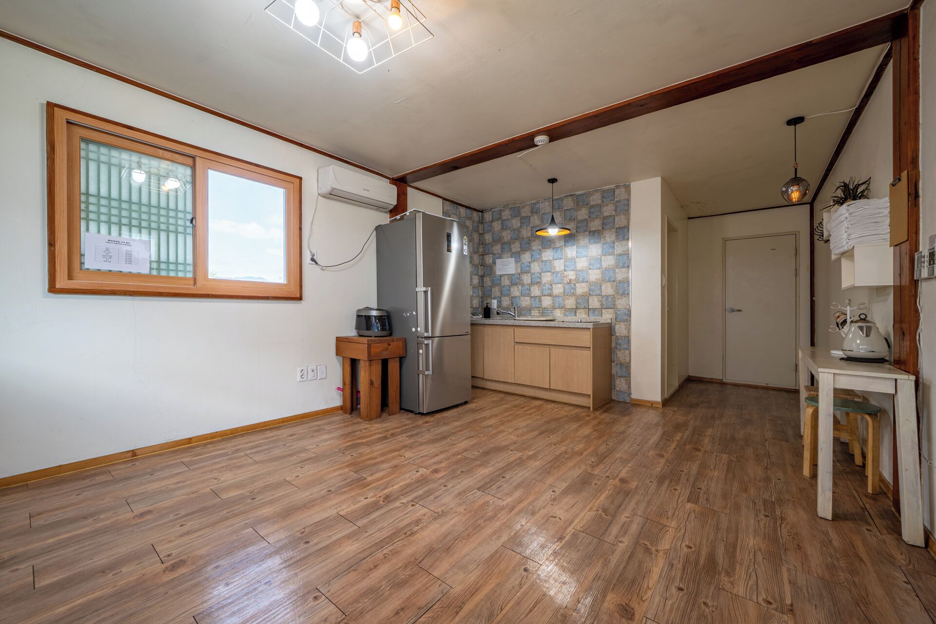 A kitchen with wooden flooring, a refrigerator, a sink, and a window with a view.