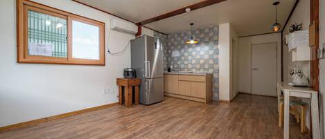 A kitchen with wooden flooring, a refrigerator, a sink, and a window with a view.
