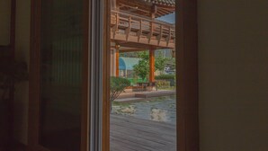 A room with a large sliding glass door leading to an outdoor area with a wooden structure and a bench. - Gyeongju West Namsan Hanok Pension (Gyeongju)
