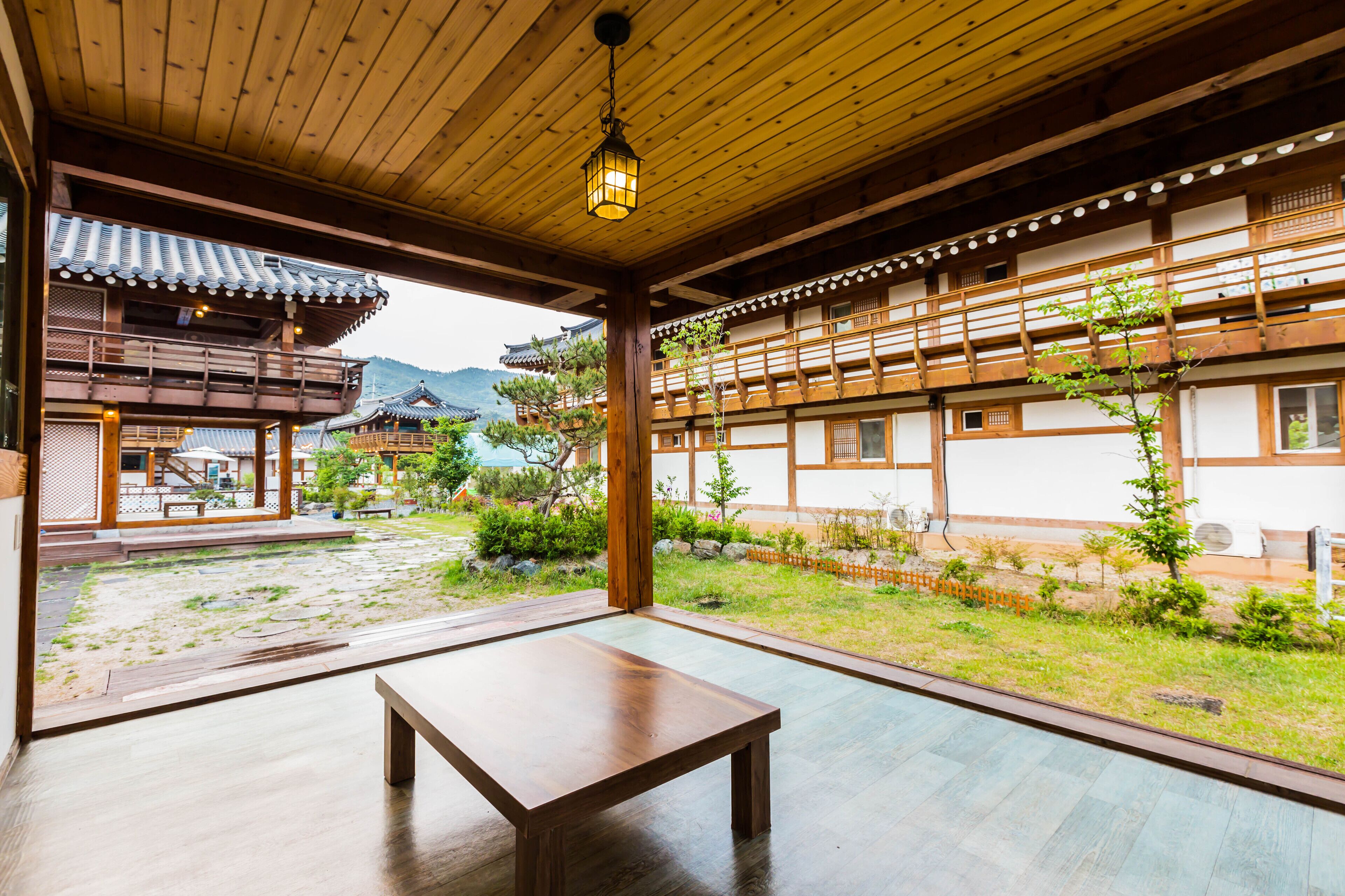 A traditional Japanese building with wooden interiors, a wooden table, and a view of a garden with a mountain in the background.