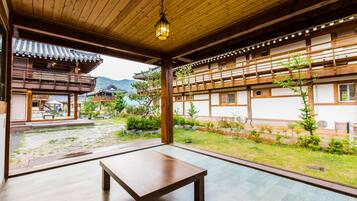 A traditional Japanese building with wooden interiors, a wooden table, and a view of a garden with a mountain in the background.