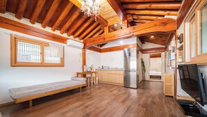 A compact kitchen with wooden beams, a built-in refrigerator, and a bench. - Gyeongju West Namsan Hanok Pension (Gyeongju)
