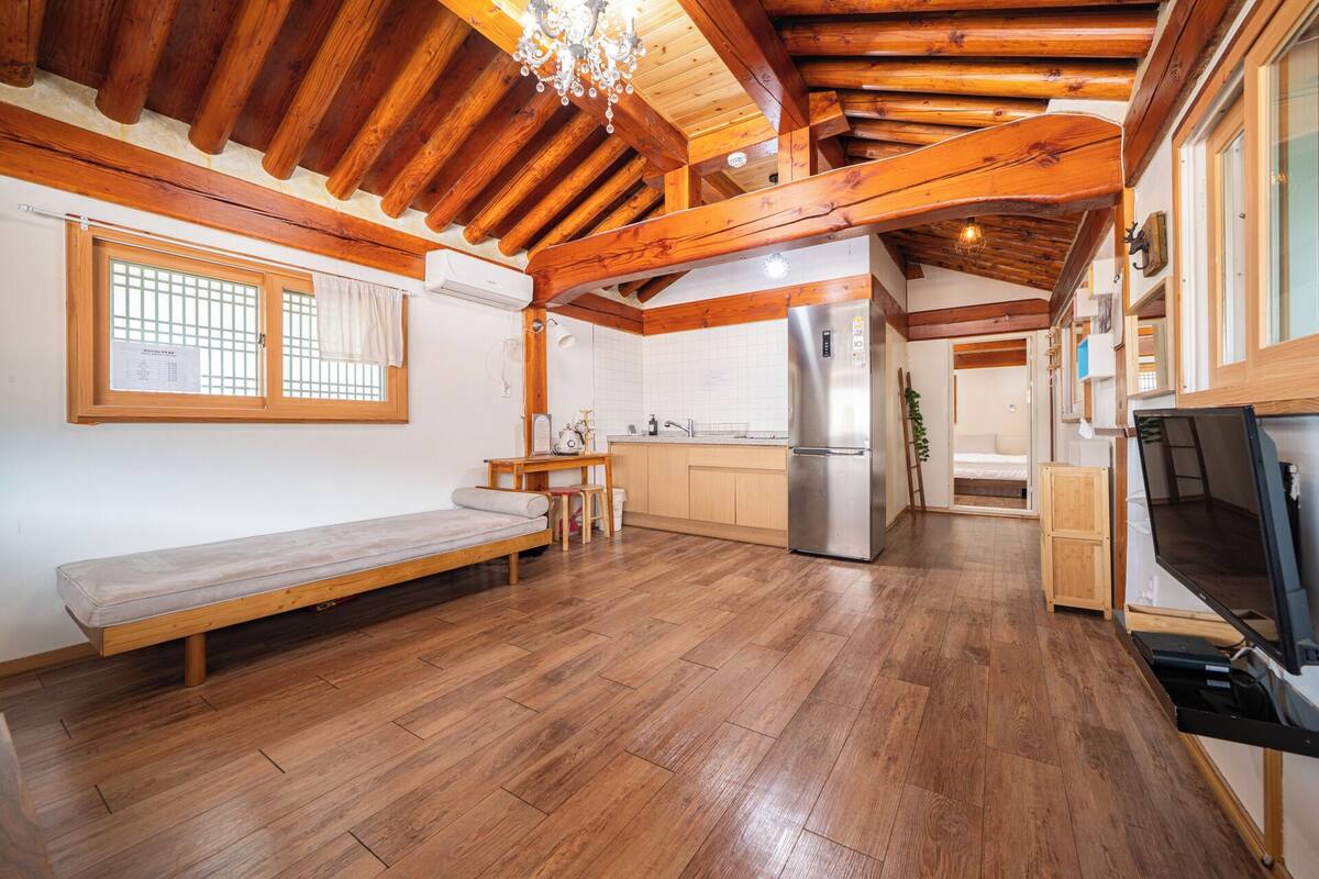 A compact kitchen with wooden beams, a built-in refrigerator, and a bench.