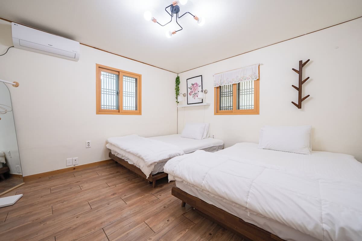 A bedroom with two single beds, a ceiling fan, and a window with a curtain.