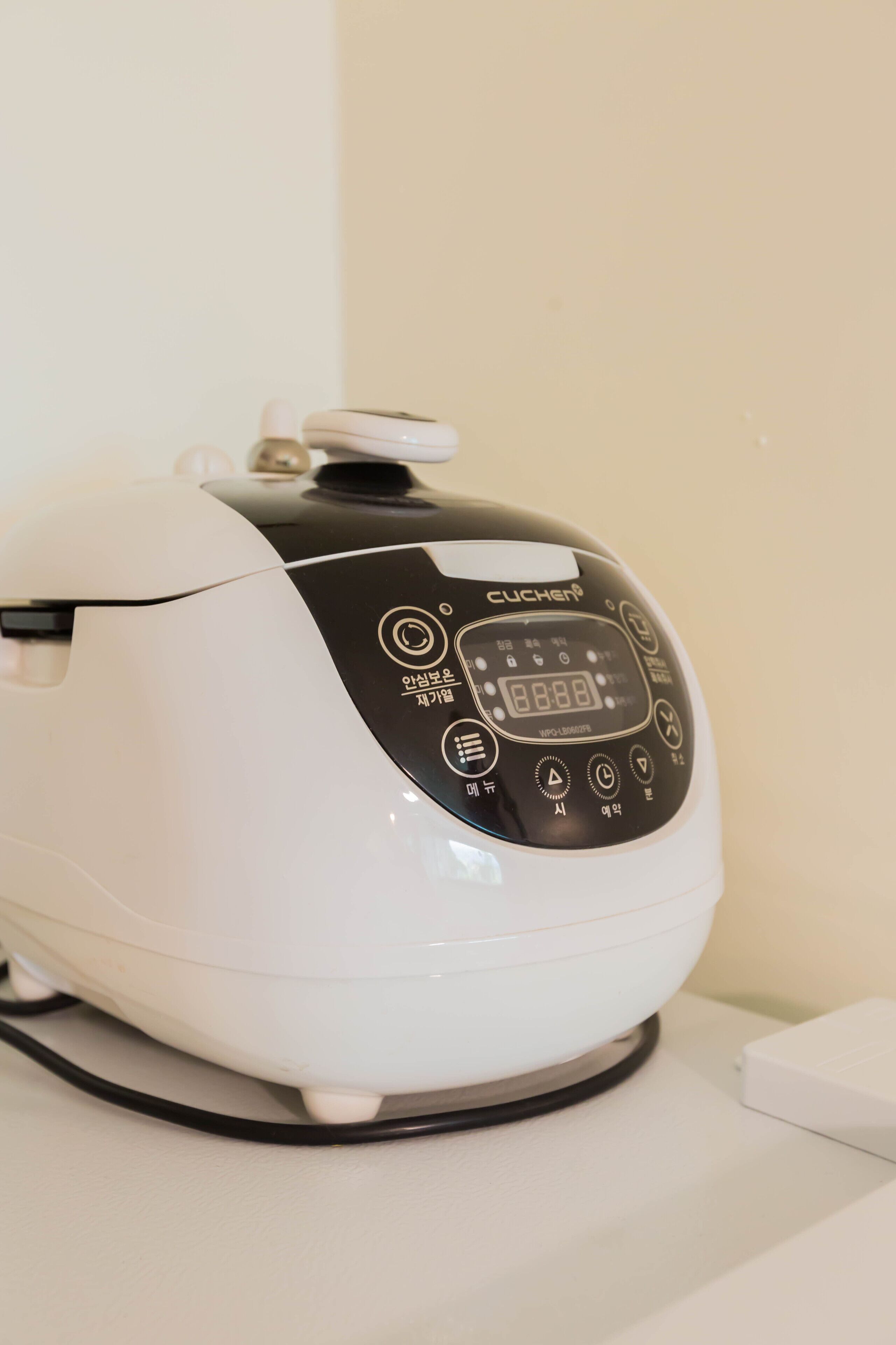 A white and black electric kettle with a digital display and control buttons.