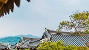 A traditional Japanese building with a wooden structure, a stone pathway, and a small pond. - Gyeongju West Namsan Hanok Pension (Gyeongju)