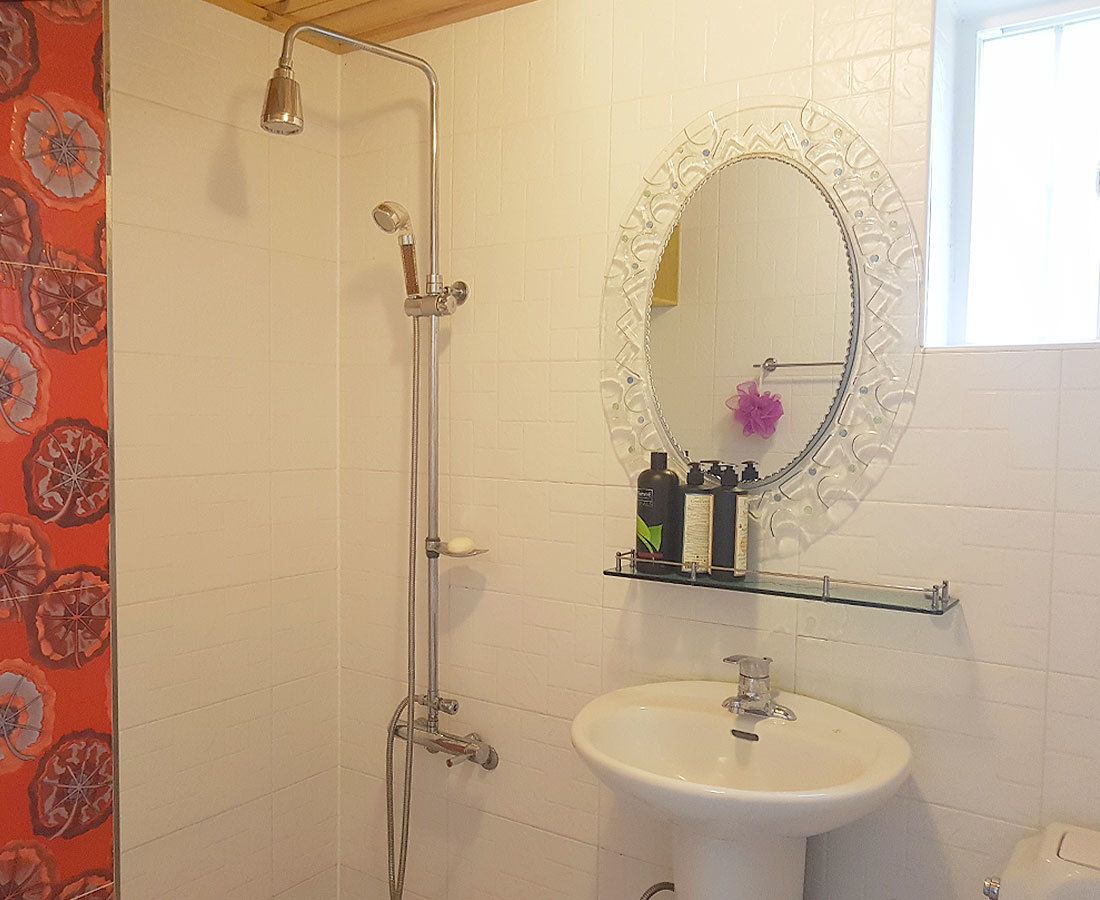 Ein Badezimmer mit Dusche, Waschbecken und einem Spiegel mit dekorativem Rahmen.