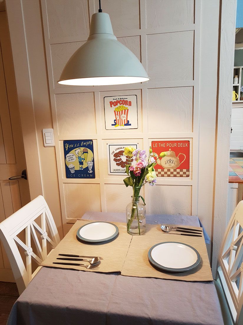 A dining table set with plates, cutlery, and a vase with flowers.