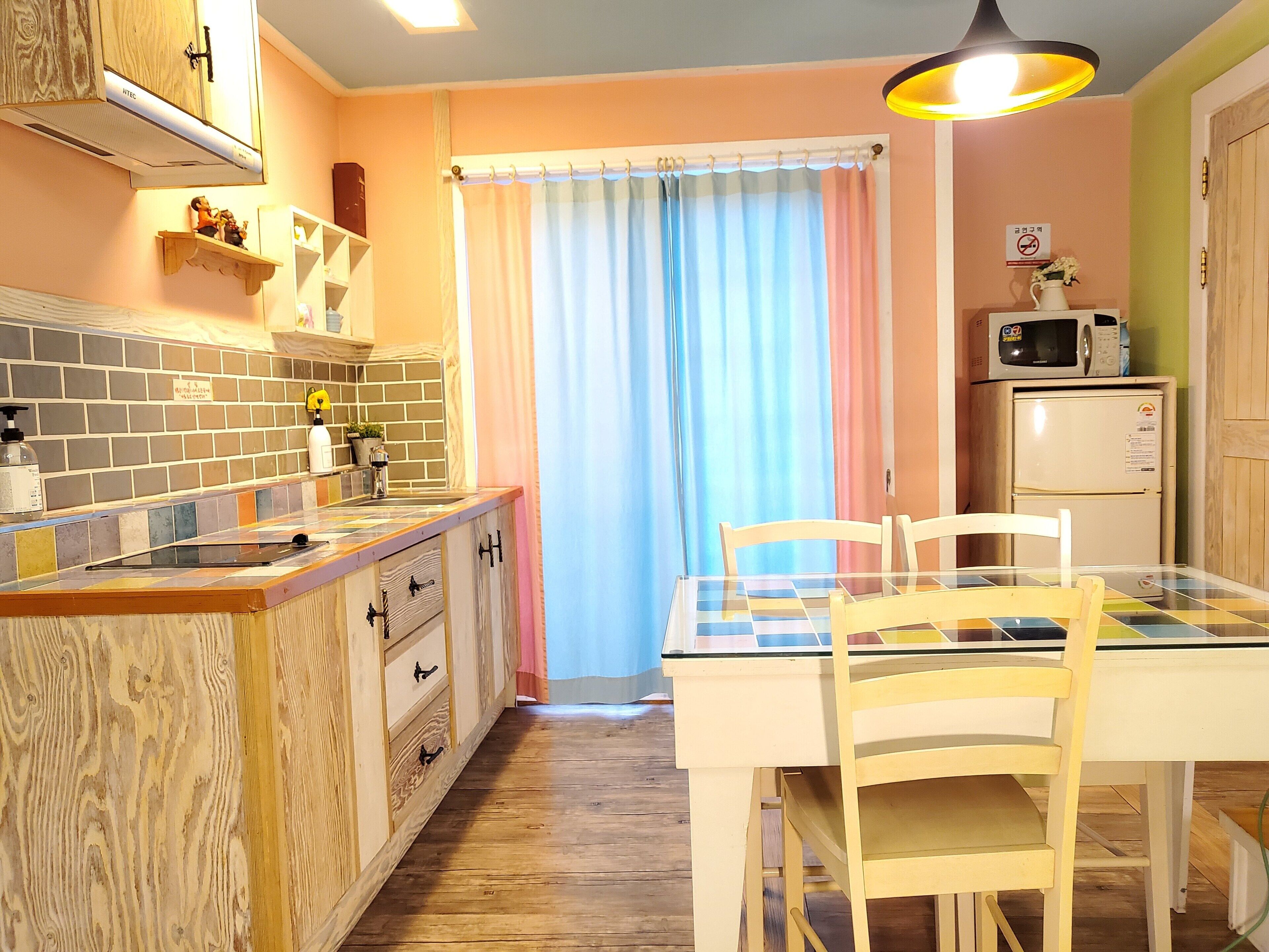 A kitchen with a wooden countertop, a sink, a refrigerator, and a dining table with chairs.