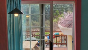 A room with a sliding glass door leading to an outdoor deck with picnic tables and a playground. - Gyeongju Olive House Pension (Gyeongju)