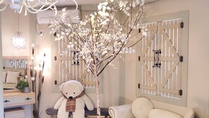 A cozy room with a white sofa, a large teddy bear, a decorative tree, and a wooden gate. - Gyeongju Olive House Pension (Gyeongju)